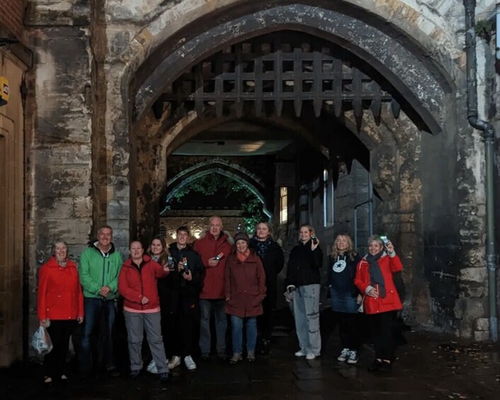 A group of people standing in front of an arched stone doorway. 4