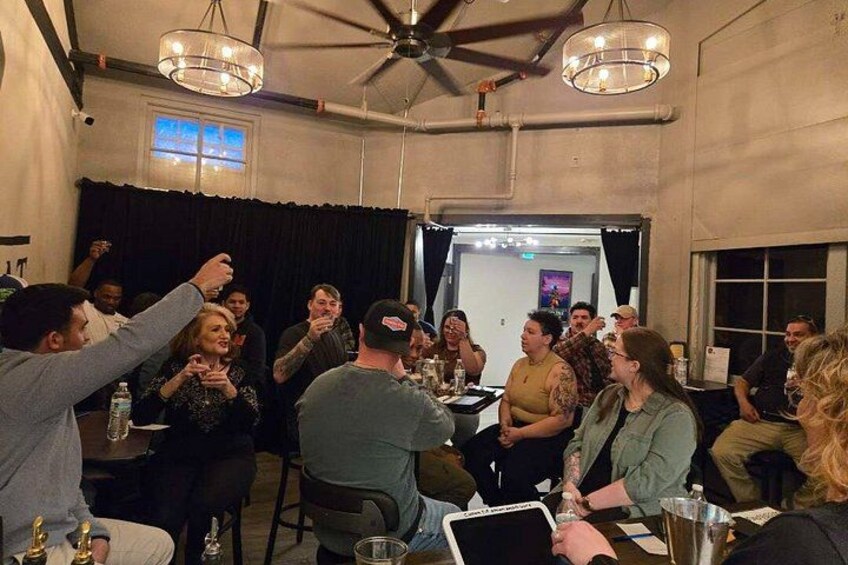 A group of people seated around a table in a room with a ceiling fan and pendant lights. 4
