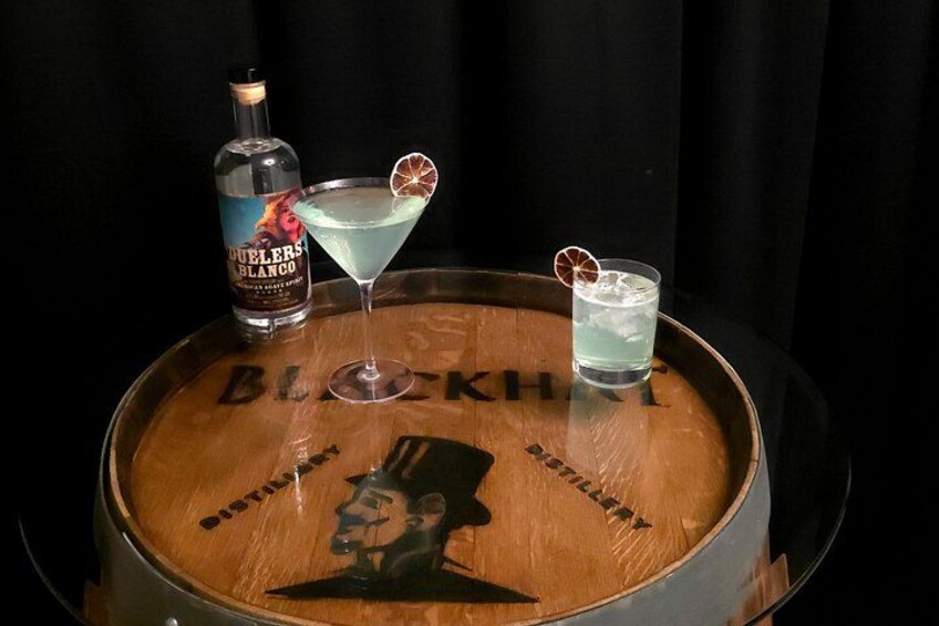 A wooden barrel with a bottle of alcohol and two drinks on top. 3