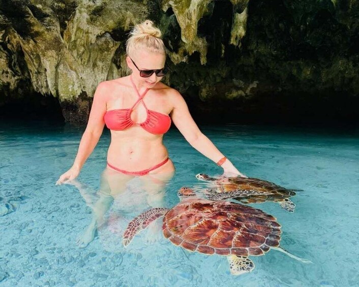 A person in a red bikini with a sea turtle in clear water. 3