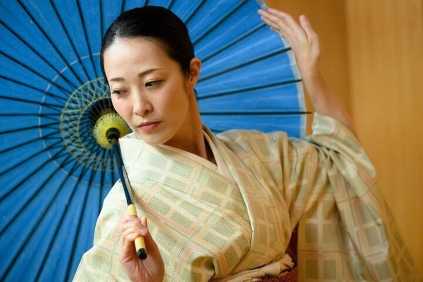 En person i kimono holder en blå vifte. 1