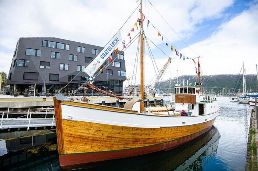 Un bote de madera amarrado en un puerto deportivo con un edificio moderno al fondo. 3
