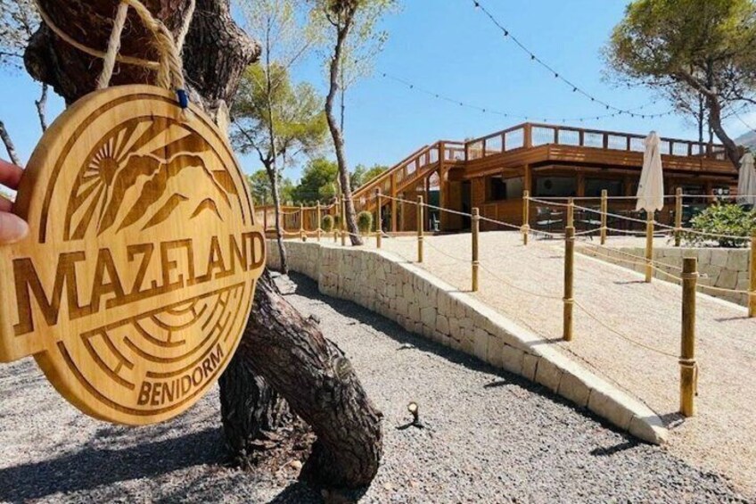 A wooden sign with 'MAZELAND BENIDOR' and a building with a wooden deck. 1