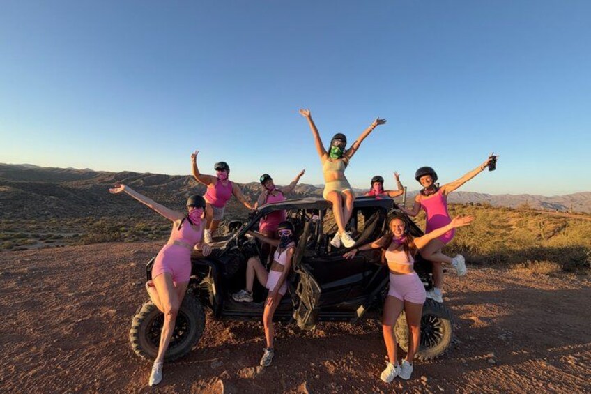Un grupo de personas en un camino de tierra, con un vehículo, rodeado de un paisaje montañoso. 4
