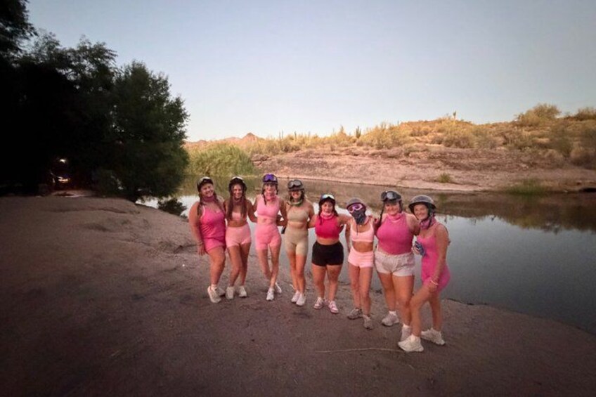 Un grupo de personas de pie junto al agua, con un paisaje desértico al fondo. 3