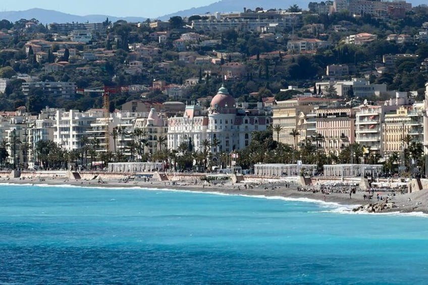 Paesaggio costiero con un edificio a cupola imponente, una spiaggia e uno sfondo collinare. 1