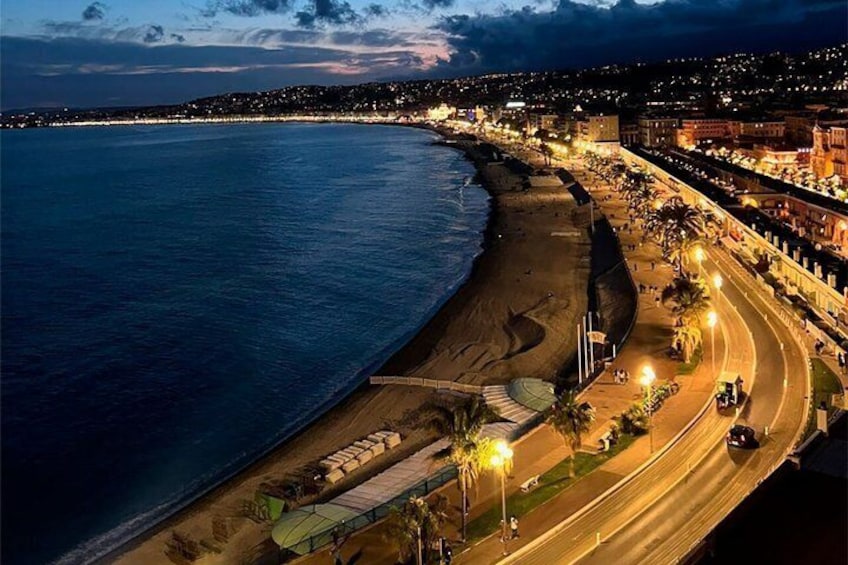 Paesaggio costiero al crepuscolo con una spiaggia, una strada e edifici lungo la riva. 3