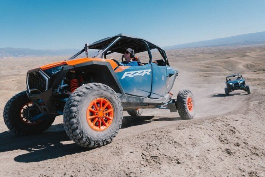 A blue off-road vehicle with orange wheels on a desert terrain. 5