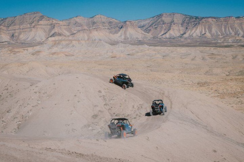 A desert landscape with two off-road vehicles on a sandy terrain. 1