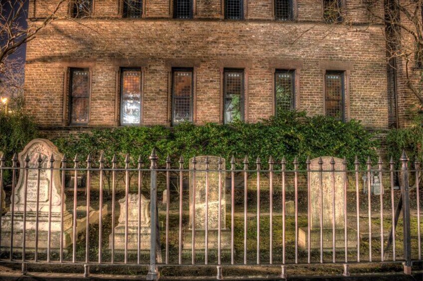 A brick building with multiple windows and a metal fence in front. 3