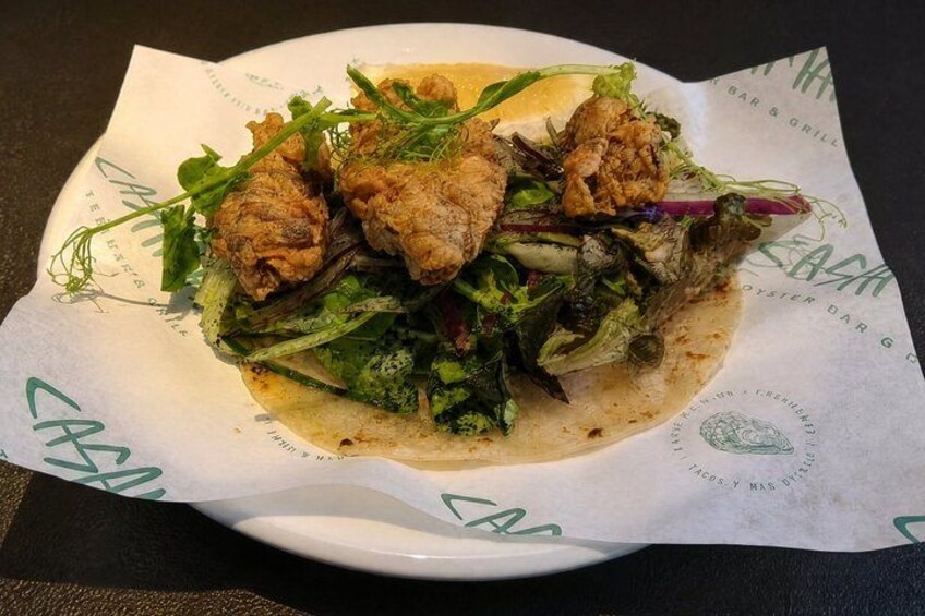 A plate of food with fried chicken and greens on a paper-lined plate. 2
