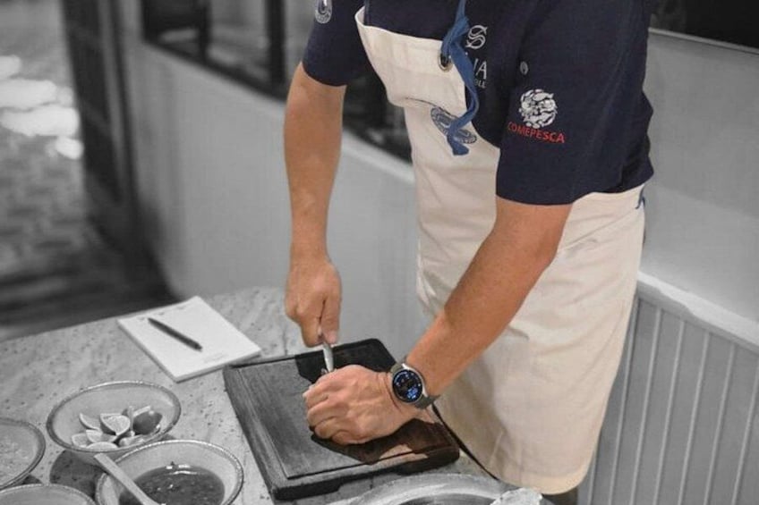 A person wearing a chef's apron and a watch, preparing food on a cutting board. 3
