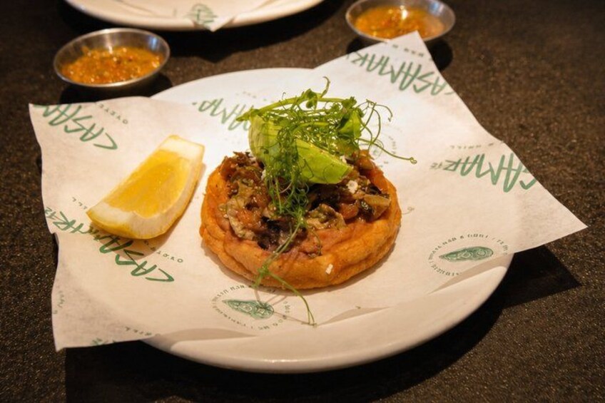 A food item on a plate with a lemon wedge and greens on the side. 5