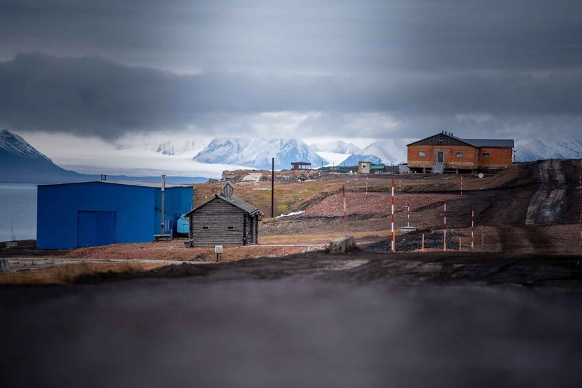 A remote settlement with buildings, a dock, and mountains in the background. 1
