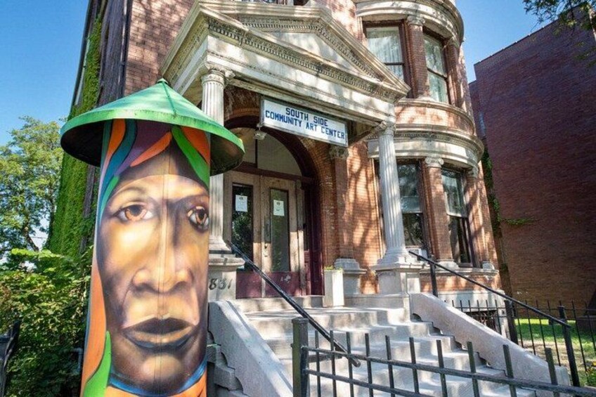 A building with a sign reading 'South Side Community Art Center' and a mural on a column. 3