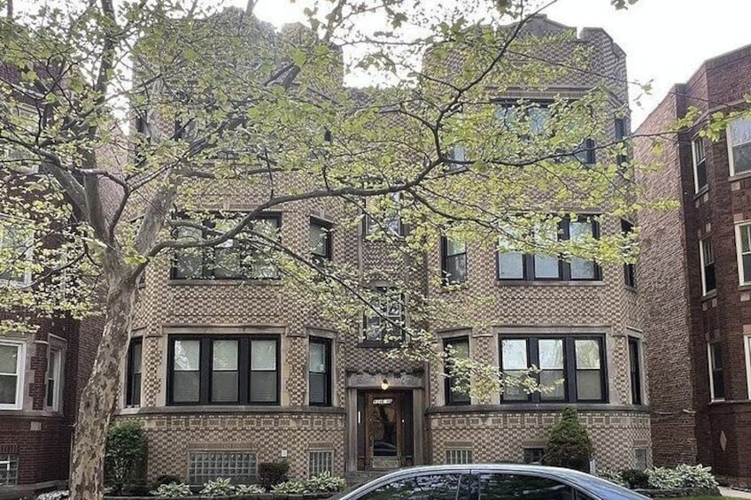 A brick building with multiple windows and a tree in front. 4