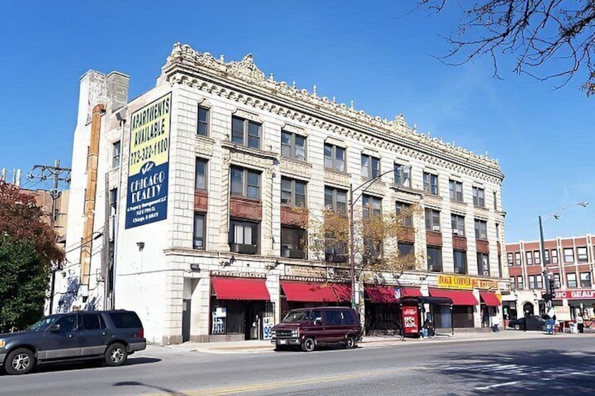 A historic building with a sign for Chicago Realty, a red awning, and parked cars on the street. 5