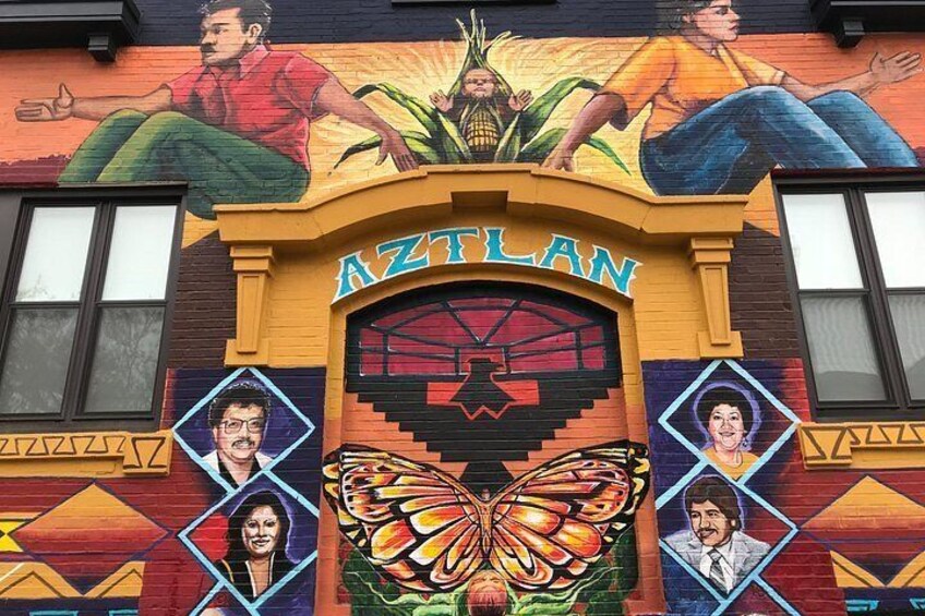 Un edificio con un mural colorido, la palabra 'AZTLAN' destacada y un diseño de mariposa grande. 1