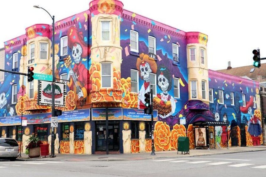 Un edificio con murales coloridos, una señal de calle y un semáforo. 4