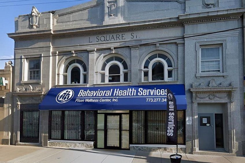 Un edificio con toldo azul que indica 'Behavioral Health Services' y 'Plunkett Wells Center, Inc.' en L Square St. 5