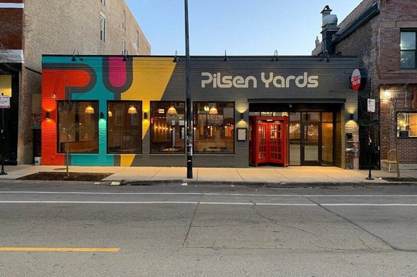 Un edificio con fachada colorida y una puerta roja, llamado Pilsen Yards. 2