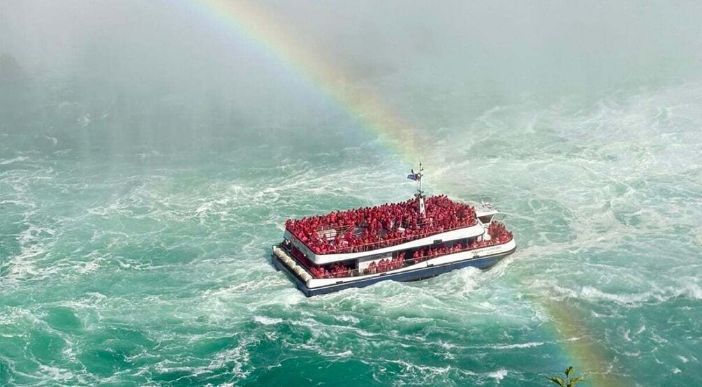 A large boat with a crowd on deck, surrounded by turbulent ocean waters and a rainbow. 1