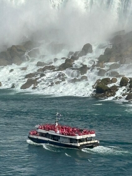 A boat with passengers navigating near a rocky coastline with a waterfall. 5