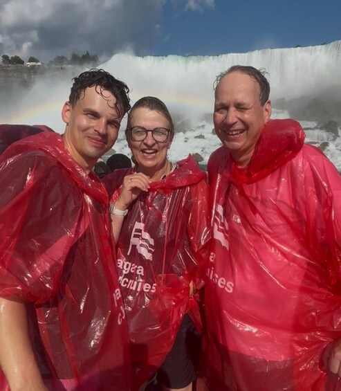 Three people in red rain ponchos with a waterfall and rainbow in the background. 2