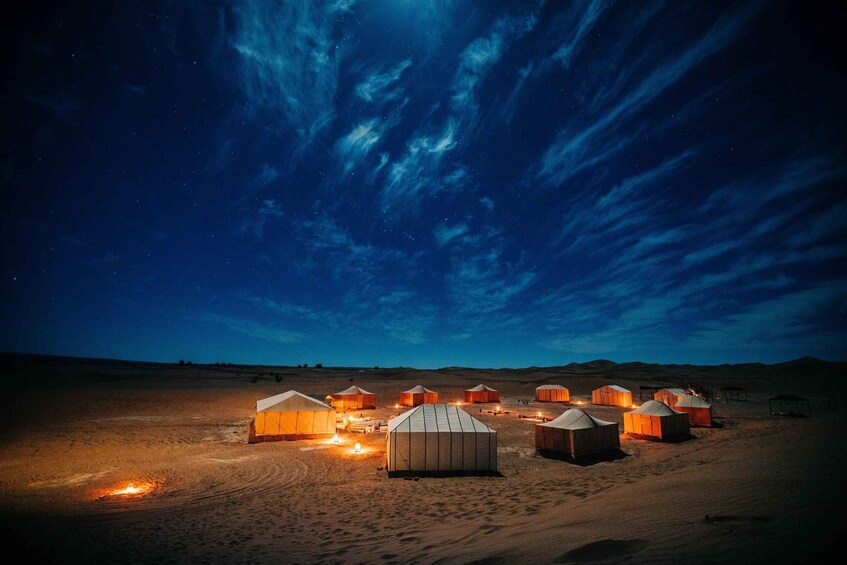 Yurts lit up at night in a desert landscape under a starry sky. 2