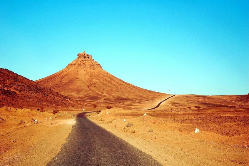 A road leading to a large, pyramid-shaped mountain in a desert landscape. 4