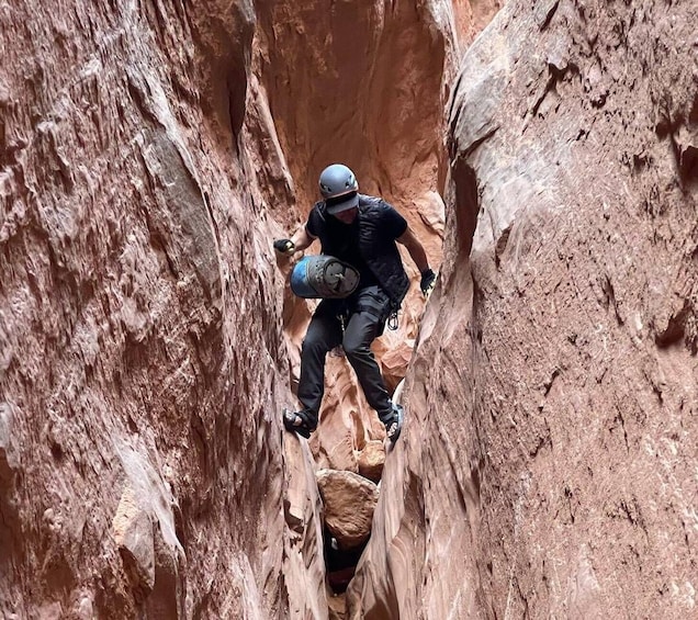 A person climbing a narrow canyon with a helmet and harness. 1