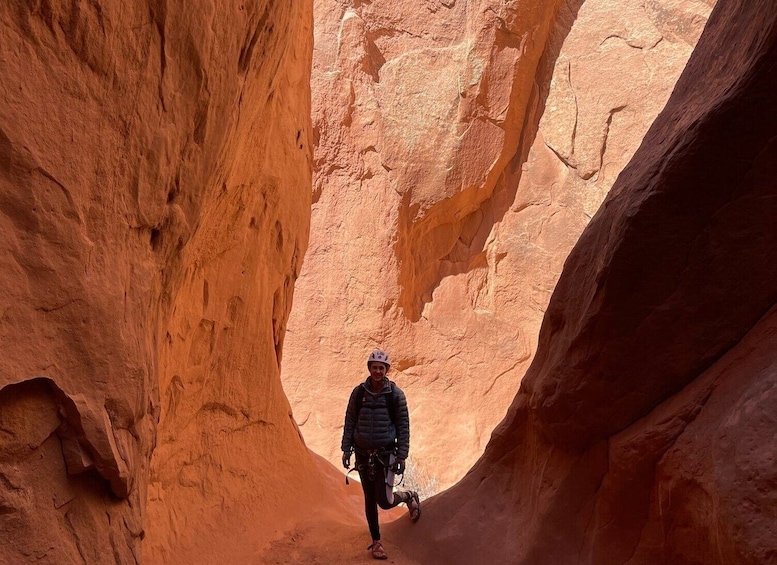 A person standing in a narrow canyon with red rock walls. 4