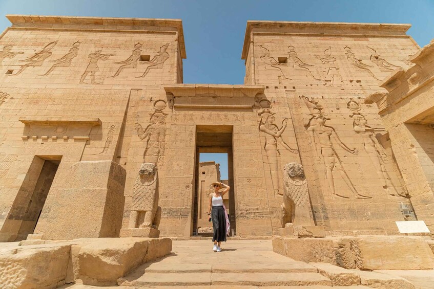 A person standing in front of an ancient Egyptian temple with hieroglyphics and statues. 5