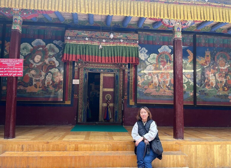 A person sitting on steps in front of a temple with colorful murals and a traditional entrance. 4