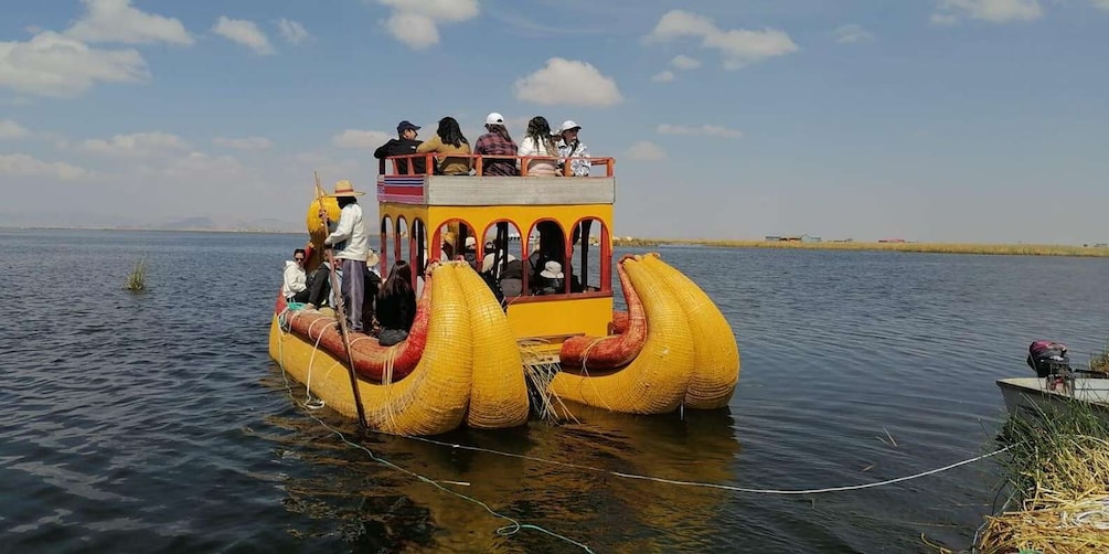 A yellow boat with a unique design, people on board, and a calm water body. 1