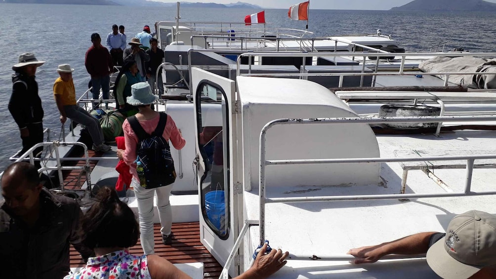 A group of people boarding a boat with a view of the sea and distant land. 5