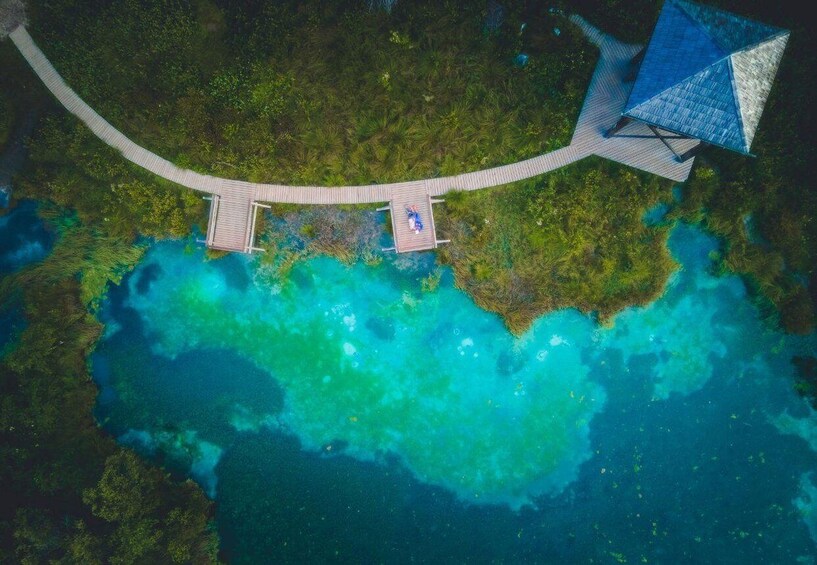 An aerial view of a tropical island with a wooden bridge connecting two parts, clear turquoise waters, and lush greenery. 1