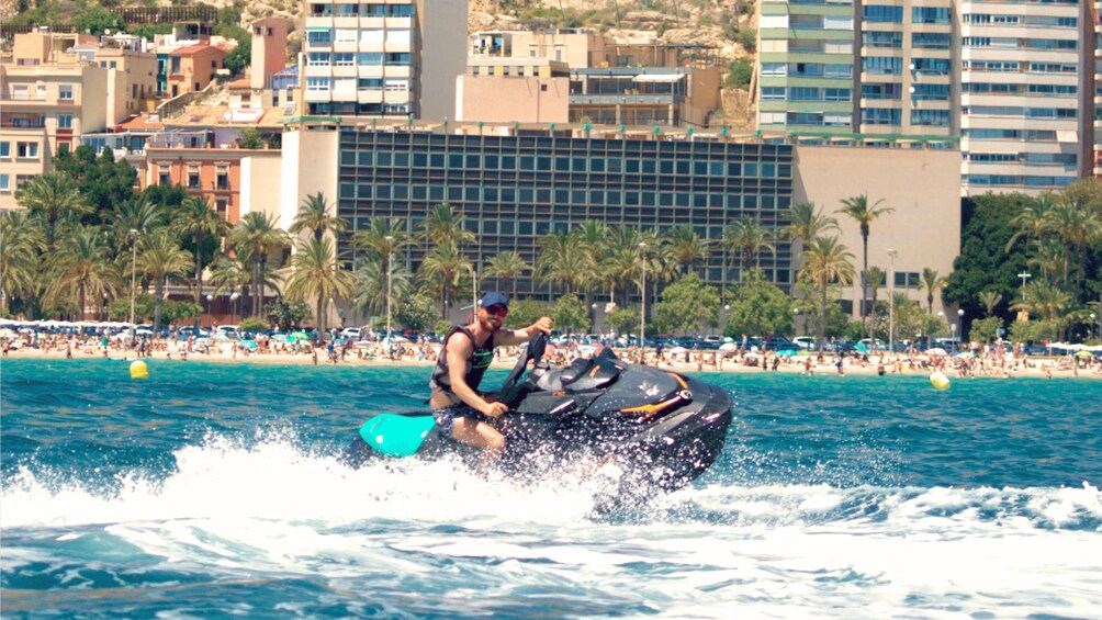 A person riding a jet ski on a beach with palm trees and buildings in the background. 3