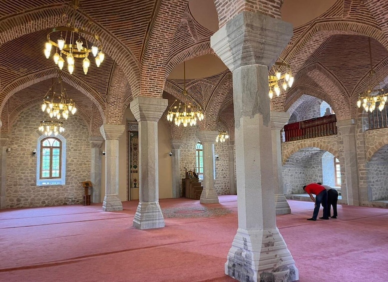 An interior with arched ceilings, stone columns, and chandeliers. 3