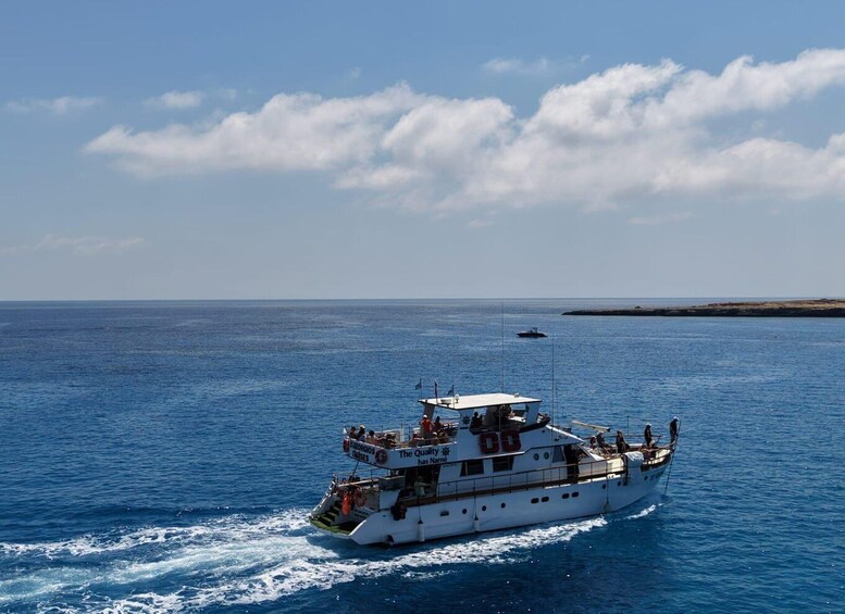 A white boat with 'The Quality' written on it, sailing on a calm blue sea with a clear sky. 4