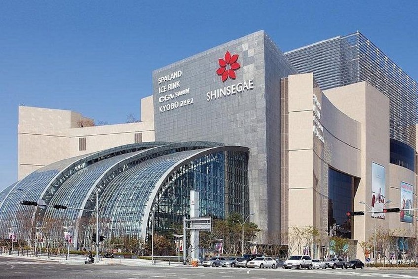 Un bâtiment moderne doté d’une façade en verre incurvée et d’une enseigne indiquant l’emplacement de la patinoire Spaland Ice Rink et du centre commercial Shinsegai. 3