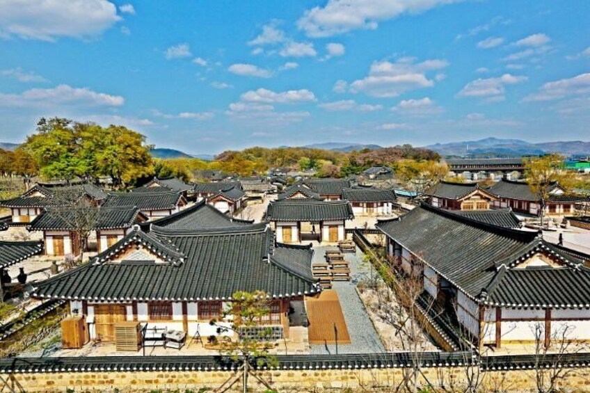 A traditional Japanese village with multiple buildings featuring dark tiled roofs and wooden structures. 2
