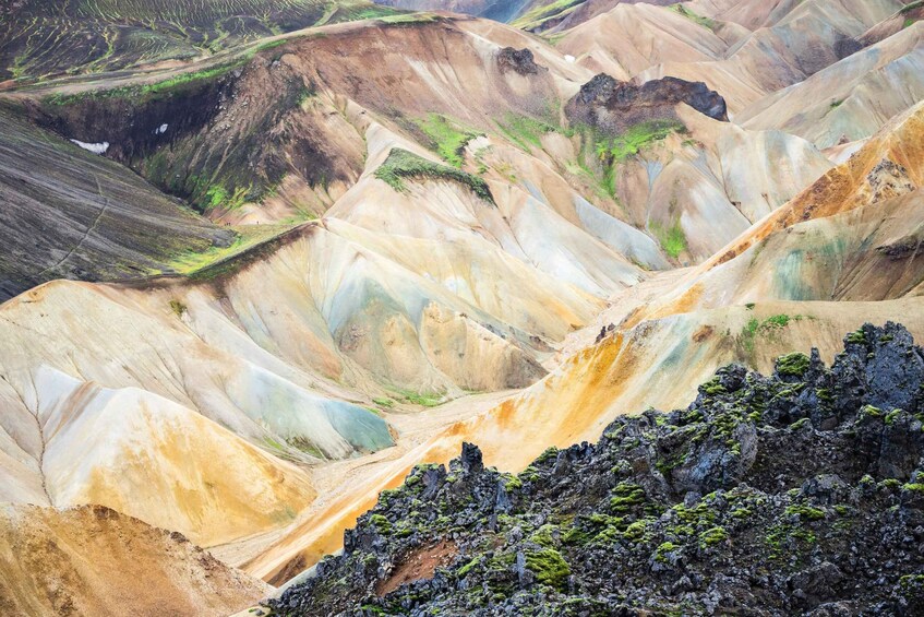 A landscape of colorful terraced hills with green vegetation patches. 1