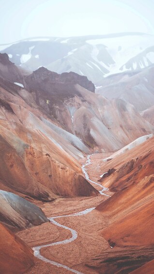 A winding river through a valley with reddish-brown sedimentary rock formations. 2
