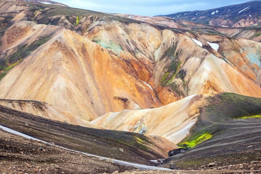 A colorful landscape with layered rock formations and a small stream. 3