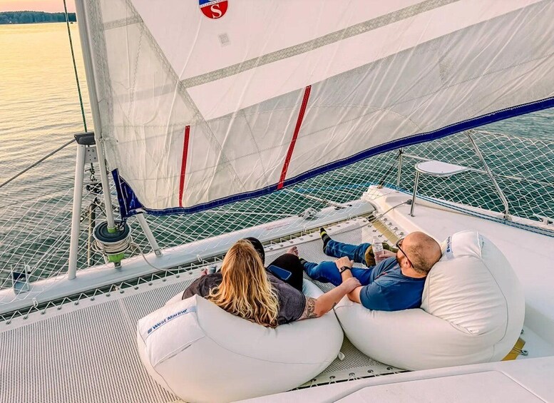 Two people relaxing on a sailboat's deck, with a calm sea and a sunset in the background. 5