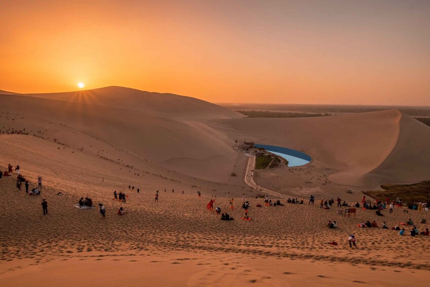 A desert landscape with sand dunes and a small body of water. 2