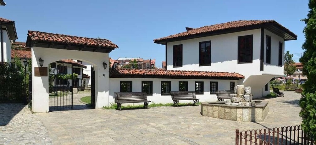 A courtyard with white buildings, red-tiled roofs, and stone benches. 2