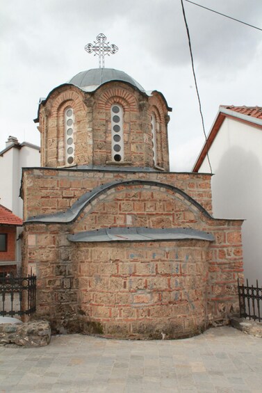 A historic church with a brick facade, a dome, and a cross on top. 3