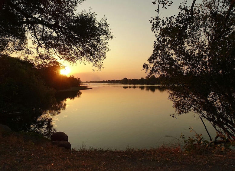 A calm river at sunset with trees on both sides. 4
